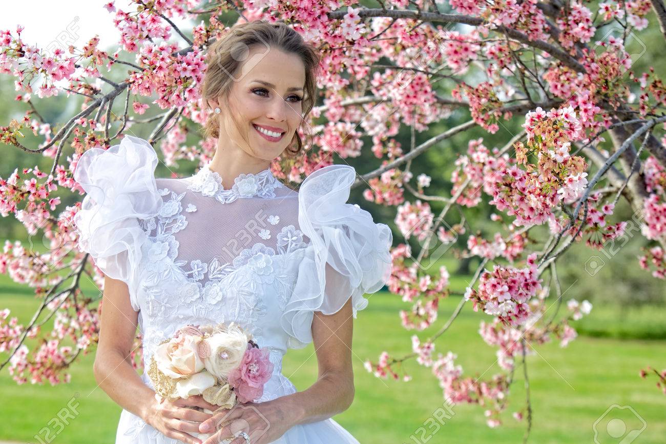 Entouré Fleurs Printemps Sur Ensoleillée Avec Jeune Cerisier En Mariée De Bouffantes Une Est Journée Robe Blanche Manches j4Ac35LqSR