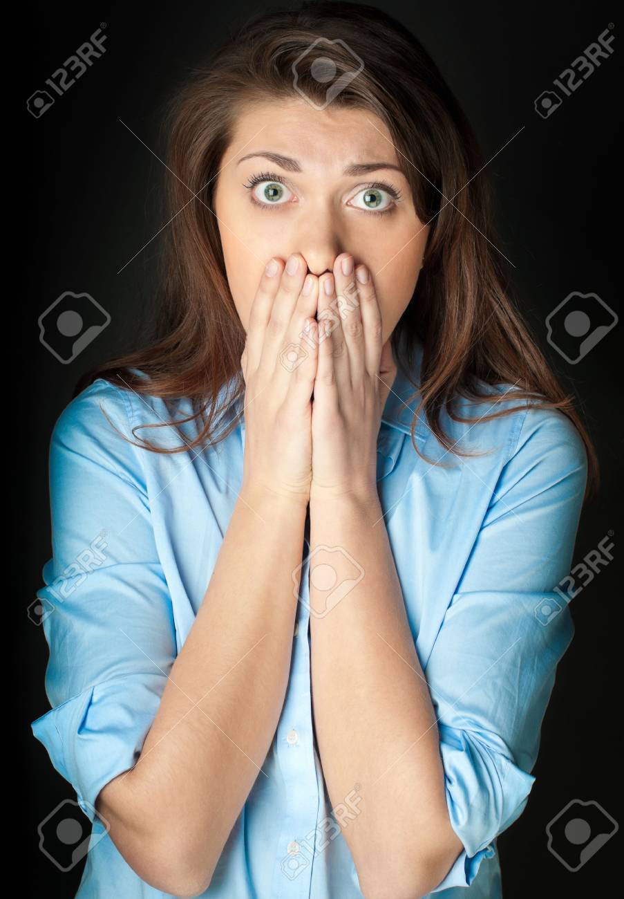 Schöne und schockierte junge Frau. Probleme oder schlechte Nachrichten. Hände auf ihr Gesicht. Blick in die Kamera, dunklen Hintergrund. Schöne und schockierte junge Frau. Probleme oder schlechte Nachrichten. Hände auf ihr Gesicht. Blick in die Kamera, dunklen Hintergrund.