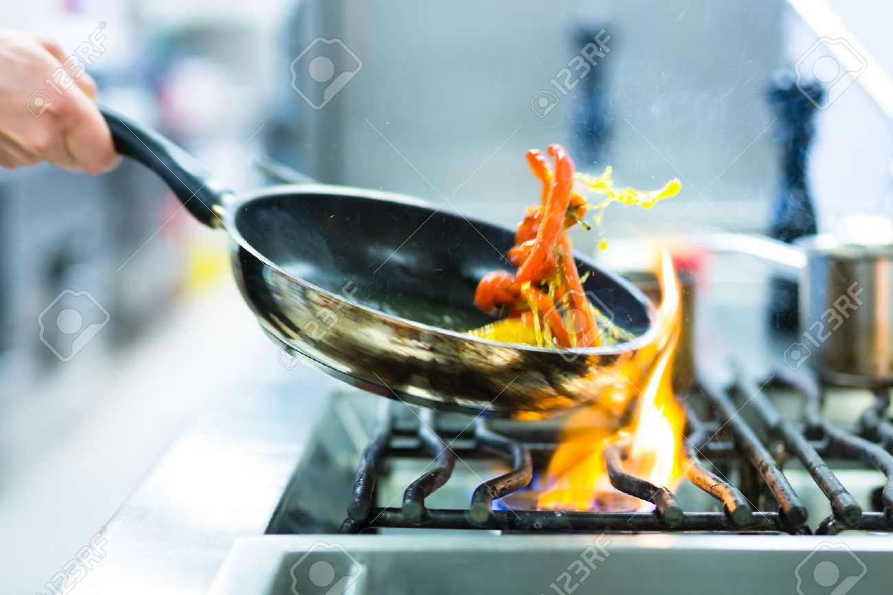 Restaurant Kitchen Chefs chef in restaurant kitchen at stove with pan, doing flambe on Restaurant Kitchen Chefs chef in restaurant kitchen at stove with pan, doing flambe on