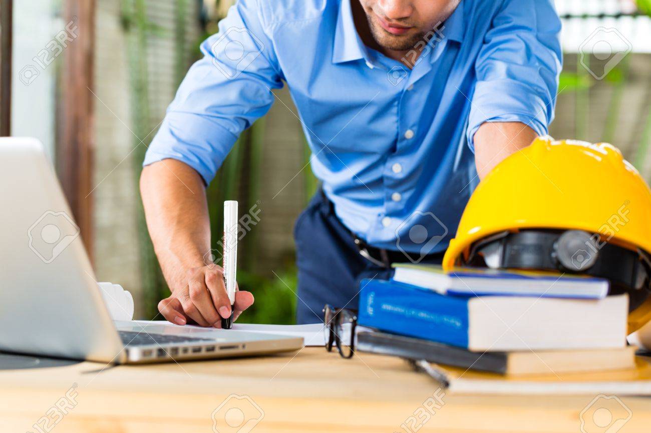 フリーランサー 建築家の設計またはドラフト彼の机の上に自宅での作業は 本やノート パソコンとヘルメット ヘルメット の写真素材 画像素材 Image