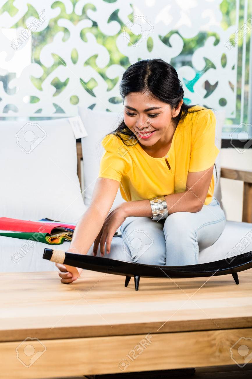 アジアのインドネシア人女性色および材料のカタログと家具店のショールームでソファ ソファに座って の写真素材 画像素材 Image