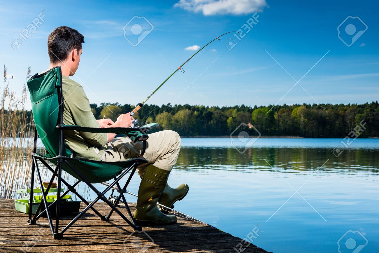 43779813-man-fishing-at-lake-sitting-on-jetty-close-to-the-water.jpg