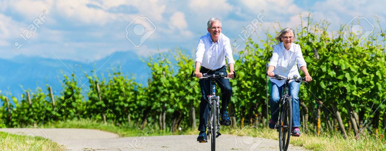 Seniors riding bicycle in vineyard together, panorama picture - 47846996 Seniors riding bicycle in vineyard together, panorama picture - 47846996