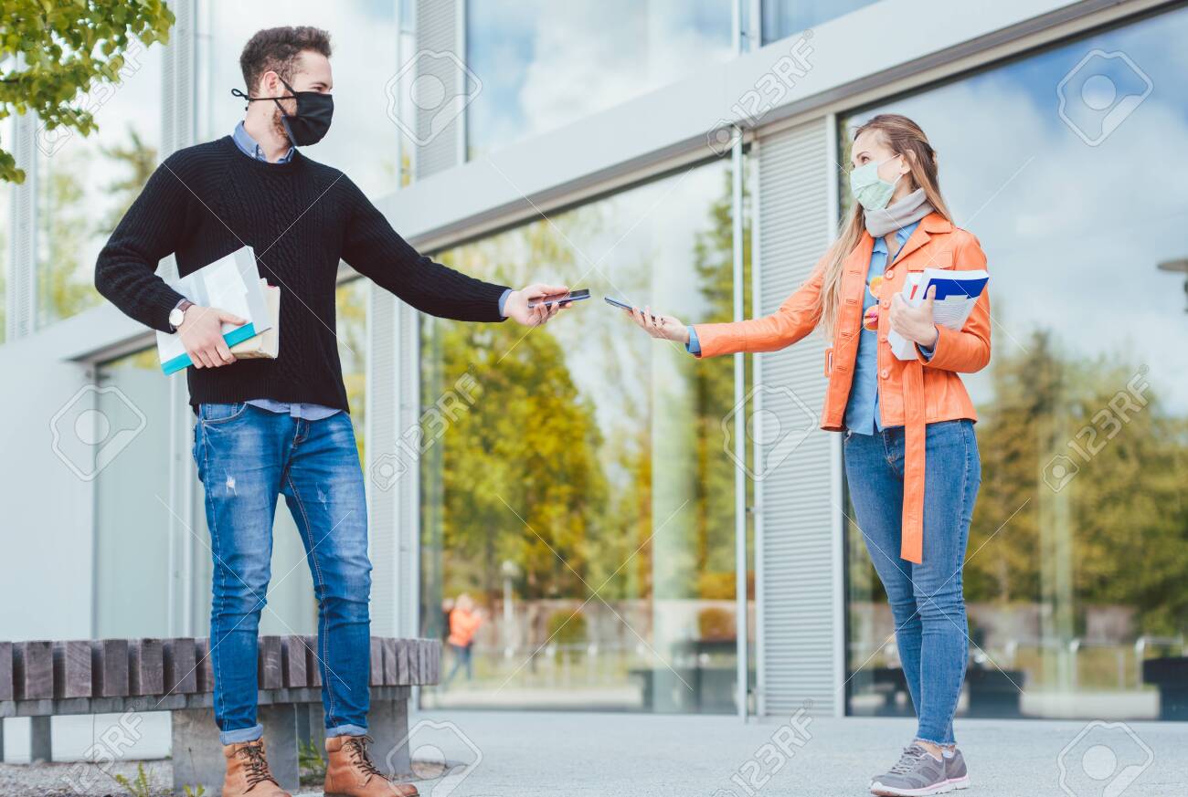 Two students during coronavirus crises with mobile phones and contract tracing app - 146463439 Two students during coronavirus crises with mobile phones and contract tracing app - 146463439