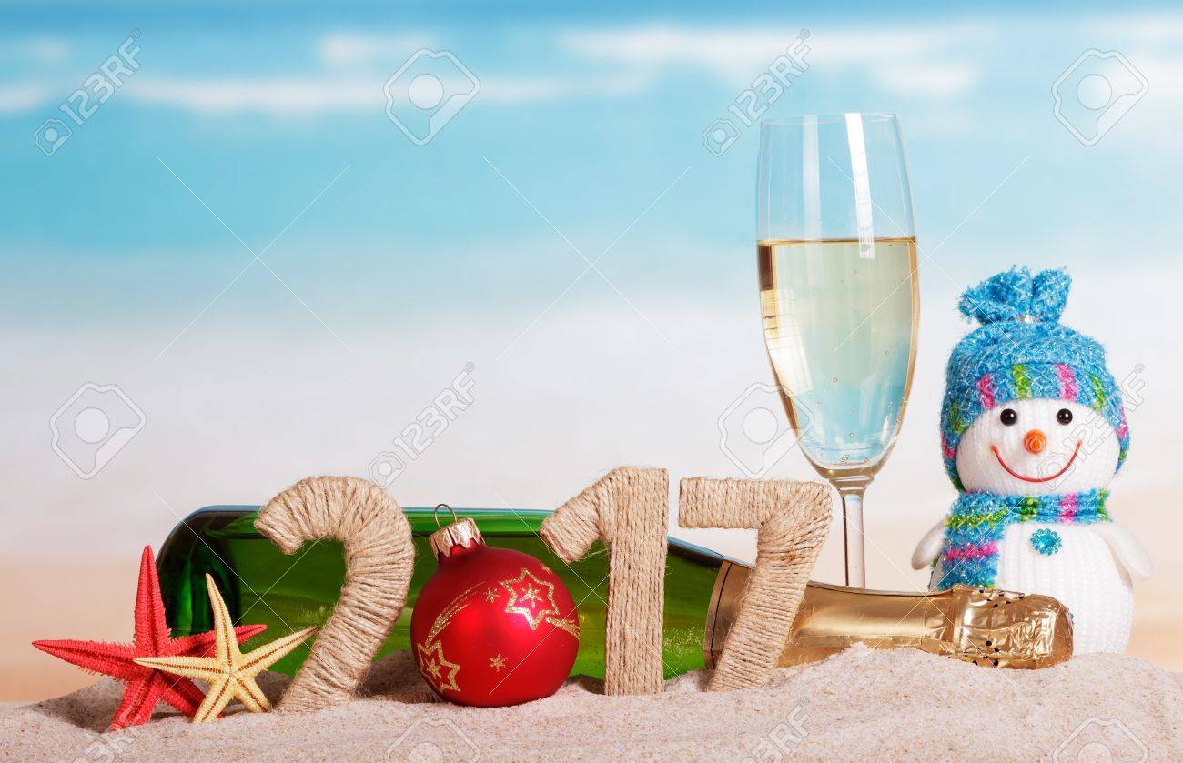 Christmas ball instead of the number in the amount of 2017 champagne bottle and glass, snowman and starfish in the sand against the sea. - 65499436 Christmas ball instead of the number in the amount of 2017 champagne bottle and glass, snowman and starfish in the sand against the sea. - 65499436