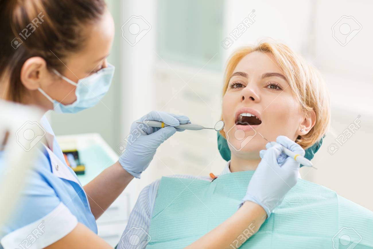 Woman dentist checks the teeth of the girl in the dental office. - 120822769 Woman dentist checks the teeth of the girl in the dental office. - 120822769