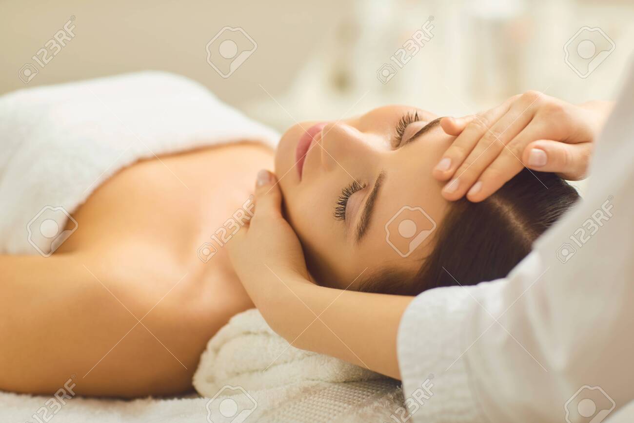Spa treatment at beauty salon. A young woman gets a facial massage at the cosmetology center. - 122063919 Spa treatment at beauty salon. A young woman gets a facial massage at the cosmetology center. - 122063919