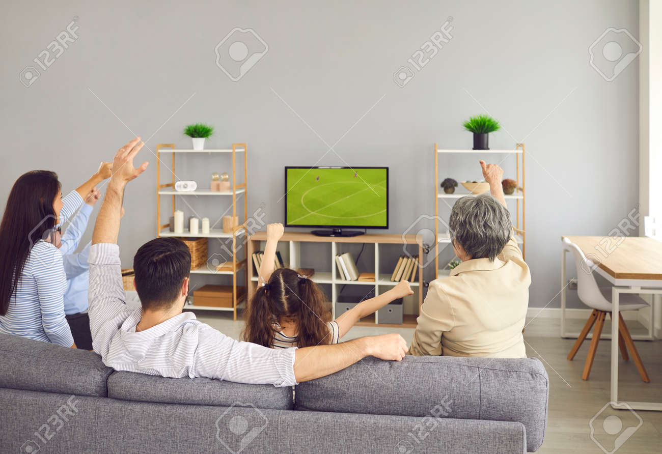 Super animado e feliz grande equipe da família assistir a partida de futebol juntos no sofá em casa. vista traseira de membros da família jovens e mais velhos sentados com os braços levantados enquanto assistia a um jogo na tv. - 173819013 Super animado e feliz grande equipe da família assistir a partida de futebol juntos no sofá em casa. vista traseira de membros da família jovens e mais velhos sentados com os braços levantados enquanto assistia a um jogo na tv. - 173819013
