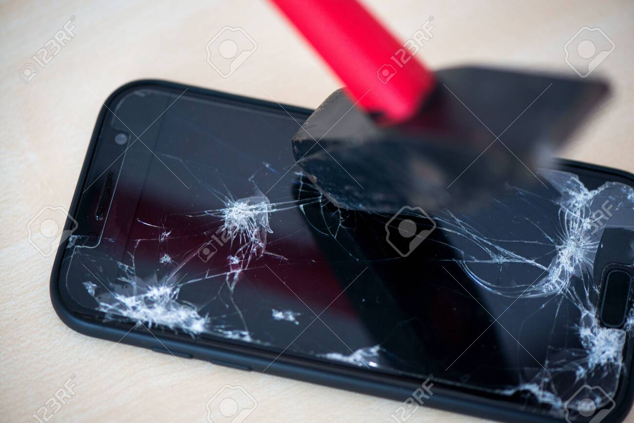 Hammer cracking on smartphone. Screen and display is destroyed, damaged and cracked. Concept of anger, rage and repairing electronic devices. Valid warranty - 119718894 Hammer cracking on smartphone. Screen and display is destroyed, damaged and cracked. Concept of anger, rage and repairing electronic devices. Valid warranty - 119718894