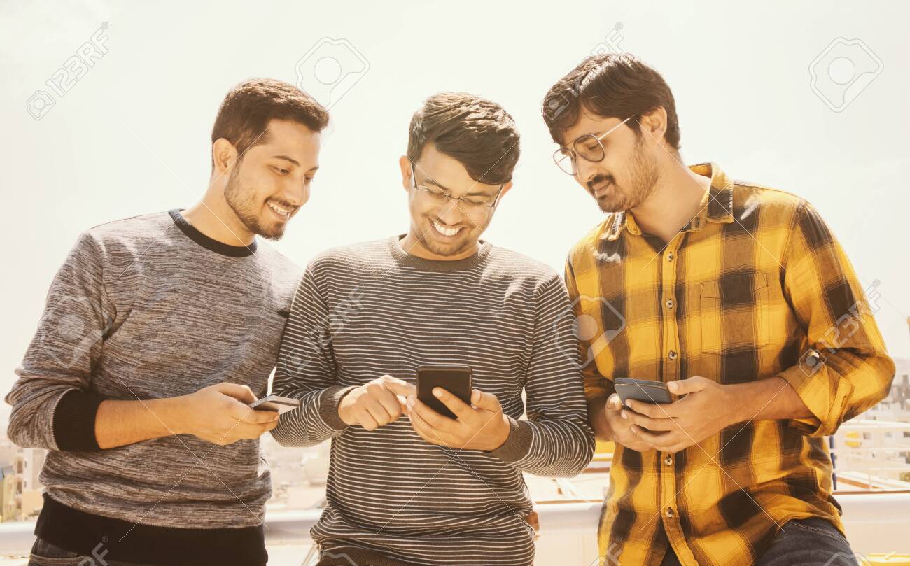 Group Of Young People Watching Mobile Phone On Terrace And 