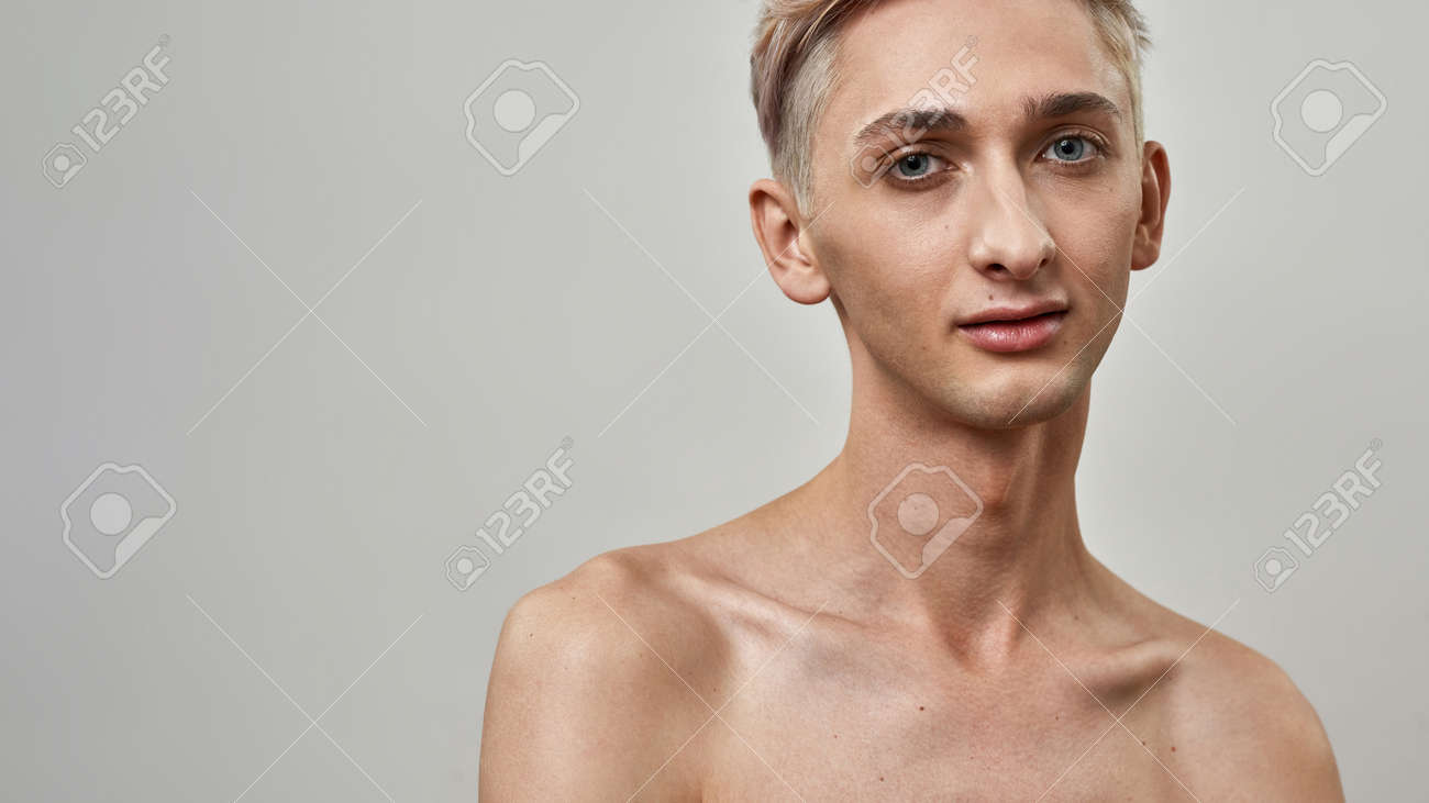  トランスジェンダー ヌード 上半身裸の両性具有のトランスジェンダーの若い男の肖像画は、明るい背景で隔離のポーズをしながらカメラを見てヌードメイクの写真素材・画像素材 Image  174367337