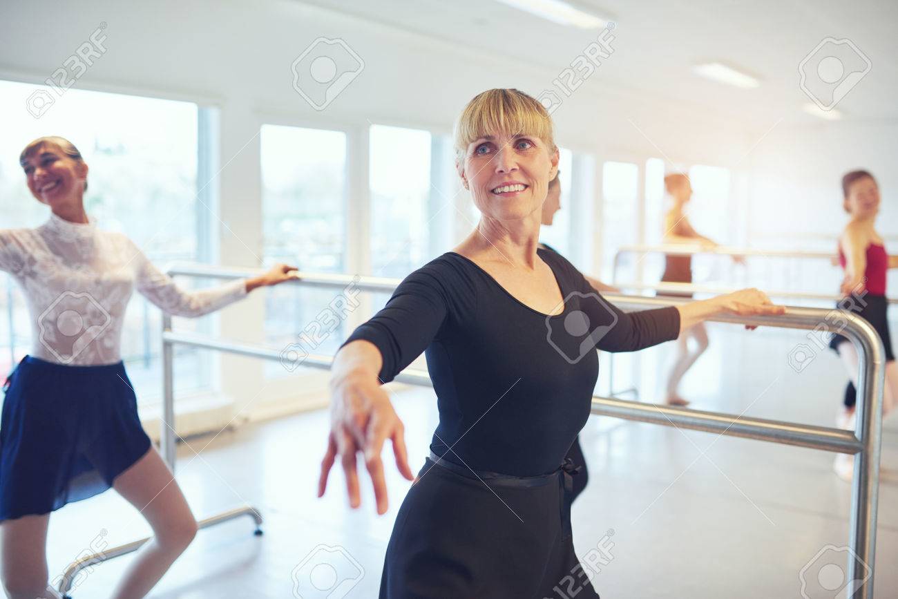 Smiling adult ballerinas standing and doing exercises in ballet.. Smiling adult ballerinas standing and doing exercises in ballet..
