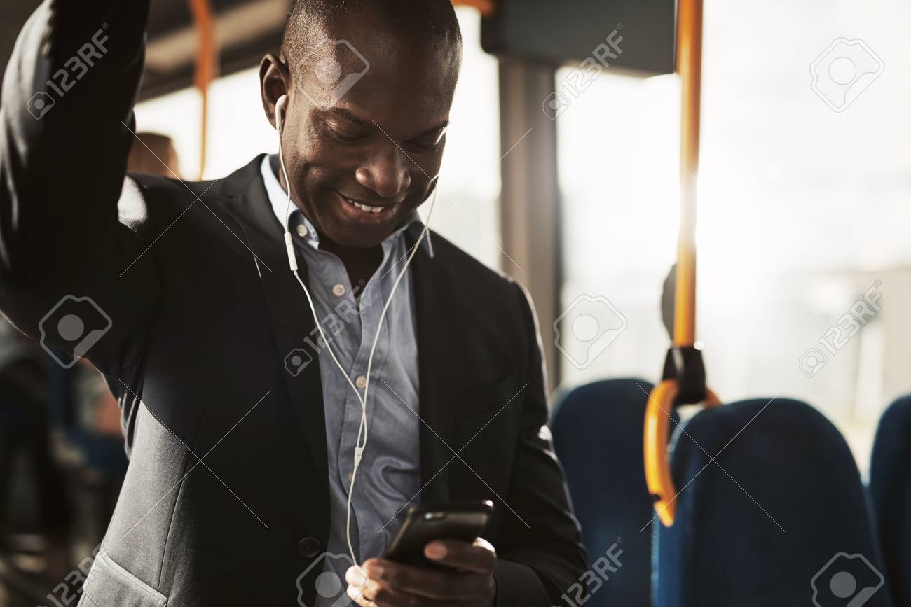 若いアフリカのビジネスマンは 朝の通勤中にバスに立っている間 イヤホンを着用し スマートフォンで音楽を聴いています の写真素材 画像素材 Image 若いアフリカのビジネスマンは 朝の通勤中にバスに立っている間 イヤホンを着用し スマートフォンで音楽を聴いています の写真素材 画像素材 Image