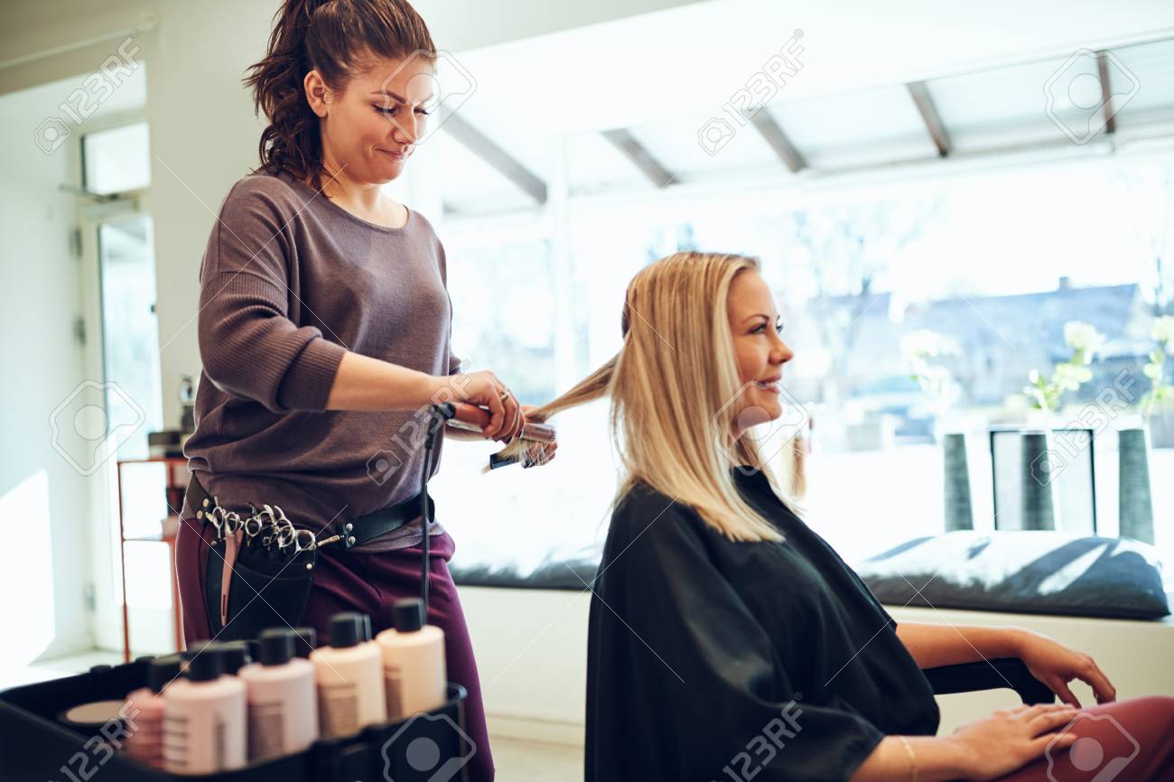 Smiling Young Blonde Woman Sitting In A Salon Chair Having Her Hair Straightened By Her Hairstylist Stock Photo, Picture And Royalty Free Image. Image 103234632. Smiling Young Blonde Woman Sitting In A Salon Chair Having Her Hair Straightened By Her Hairstylist Stock Photo, Picture And Royalty Free Image. Image 103234632.
