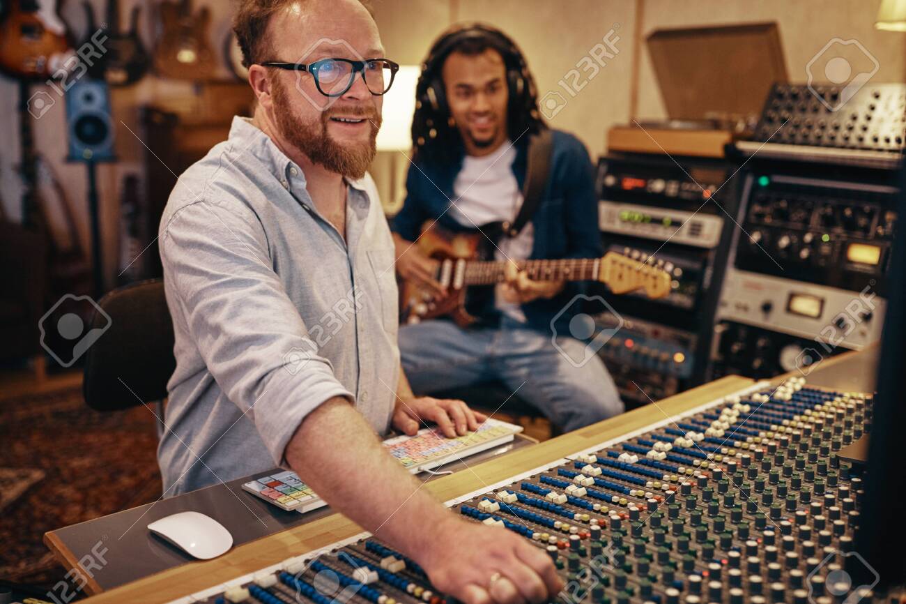 Smiling Music Producer Making Adjustments On A Soundboard With Stock Photo Picture And Royalty Free Image Image 122162938