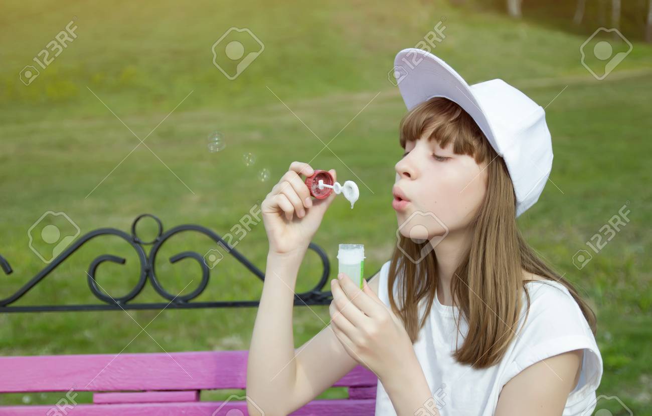 かわいい若い女の子がベンチにシャボン玉を吹いています の写真素材 画像素材 Image