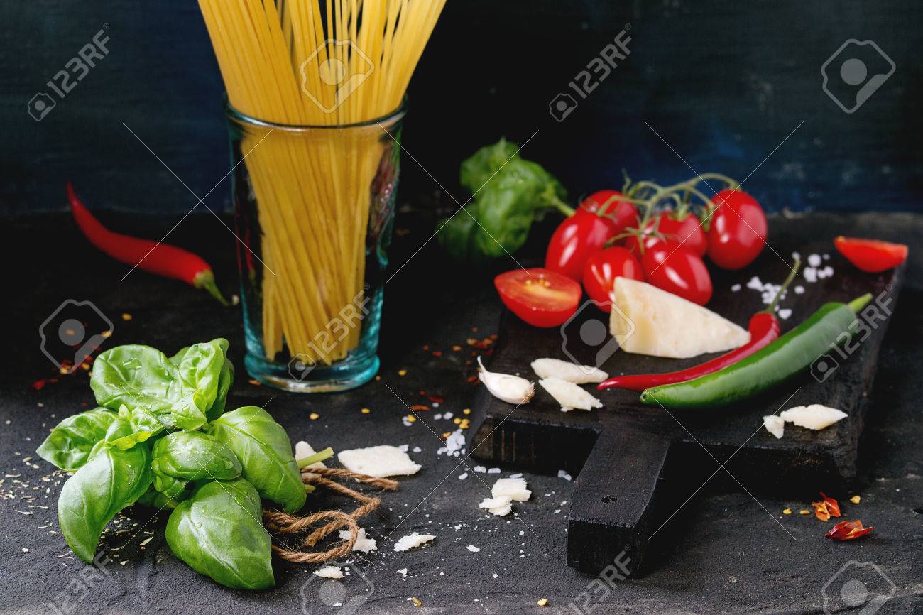 パスタ ソース トマト バジル ニンニク 唐辛子 乾燥スパゲッティ黒の上に木製のまな板にパルメザン チーズの成分はテクスチャ背景です の写真素材 画像素材 Image