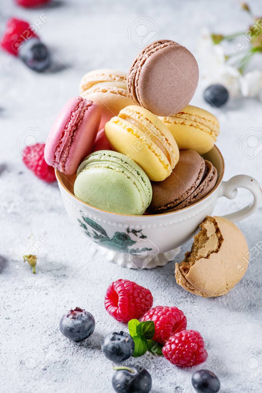Immagini Stock Varieta Di Dolci Macaron Macaron Dolci Francesi Amaretti Con Diversi Ripieni Serviti In Tazza Di Te Vintage Con Fiori Di Primavera E Bacche Fresche Su Sfondo Grigio Texture Avvicinamento