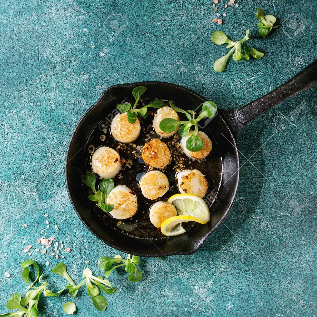 バターレモンスパイシーソースのホタテのフライドシノテは ターコイズの食感の背景にグリーンサラダを添えた鋳鉄鍋 トップビュー スペースをコピーします 正方形の画像 の写真素材 画像素材 Image