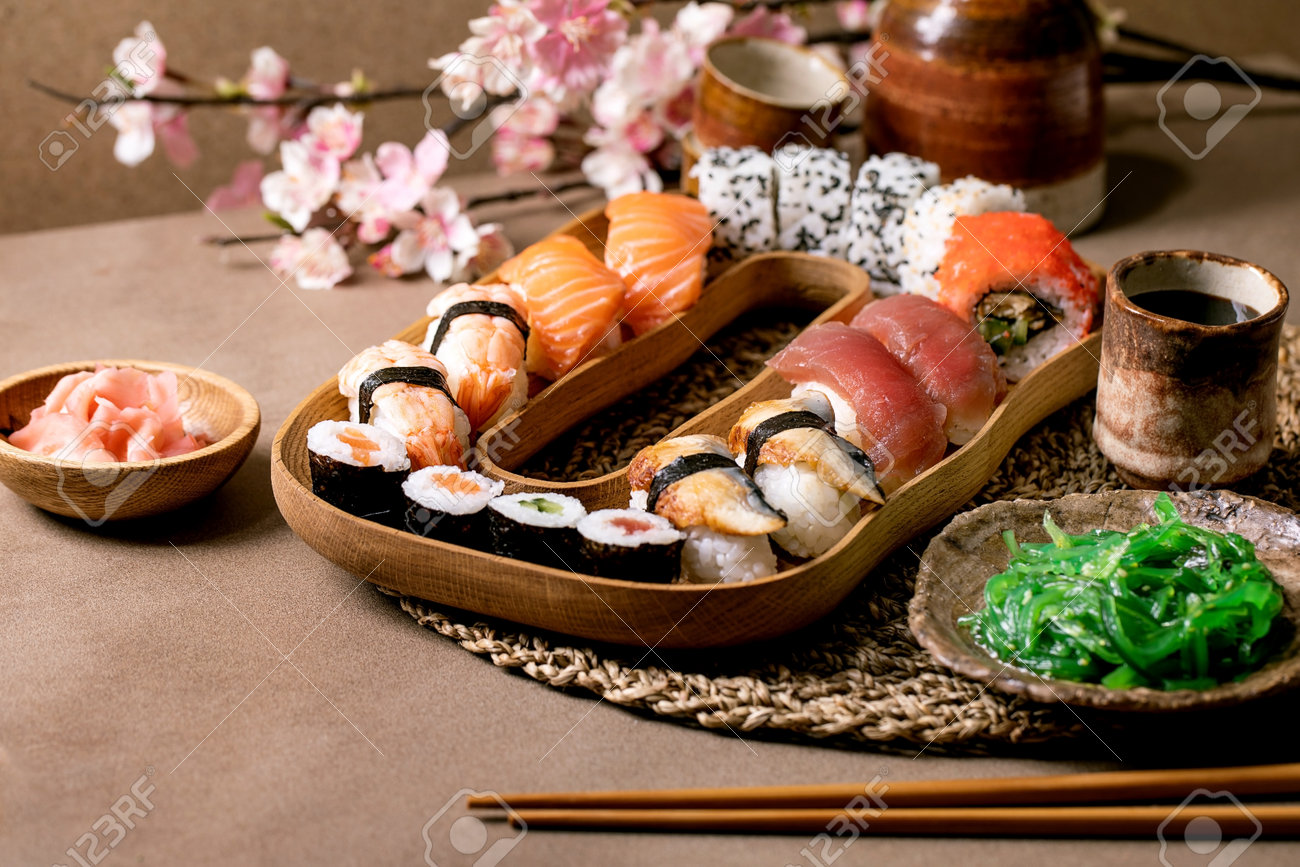 Sushi broodjes set. traditionele japanse schotel sushi broodjes met verse zalm, tonijn, paling, garnalen op rijst. serveren op houten bord met sojasaus, wakame salade op bruine tafel. sake set en voorjaar bloemen - 182674045 Sushi broodjes set. traditionele japanse schotel sushi broodjes met verse zalm, tonijn, paling, garnalen op rijst. serveren op houten bord met sojasaus, wakame salade op bruine tafel. sake set en voorjaar bloemen - 182674045