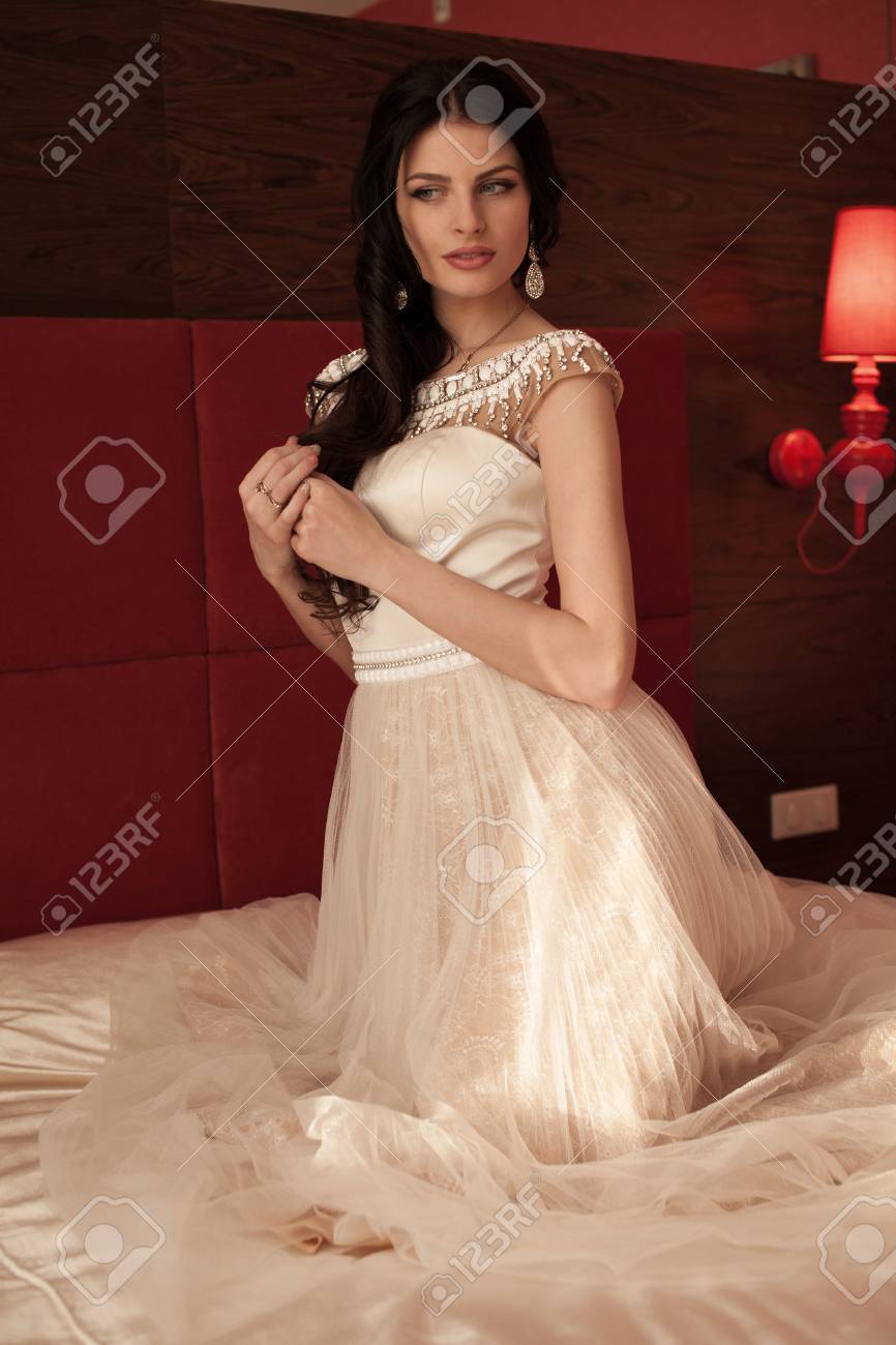 Coiffure Belle Jeune Mariée Brune Avec Des Cheveux Longs Ondulés En Bonne Santé Et Maquillage Professionnel En Robe De Mariée En Dentelle Courte