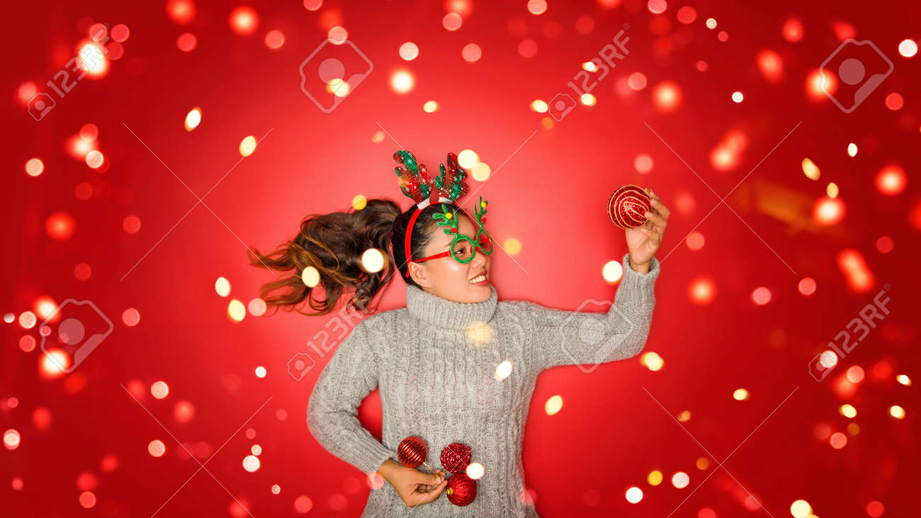 The girl is using the hand to hold the ball red decorations On a red background with christmas ornaments with led light. Top view. Christmas family traditions. Concept christmas. - 160102483 The girl is using the hand to hold the ball red decorations On a red background with christmas ornaments with led light. Top view. Christmas family traditions. Concept christmas. - 160102483