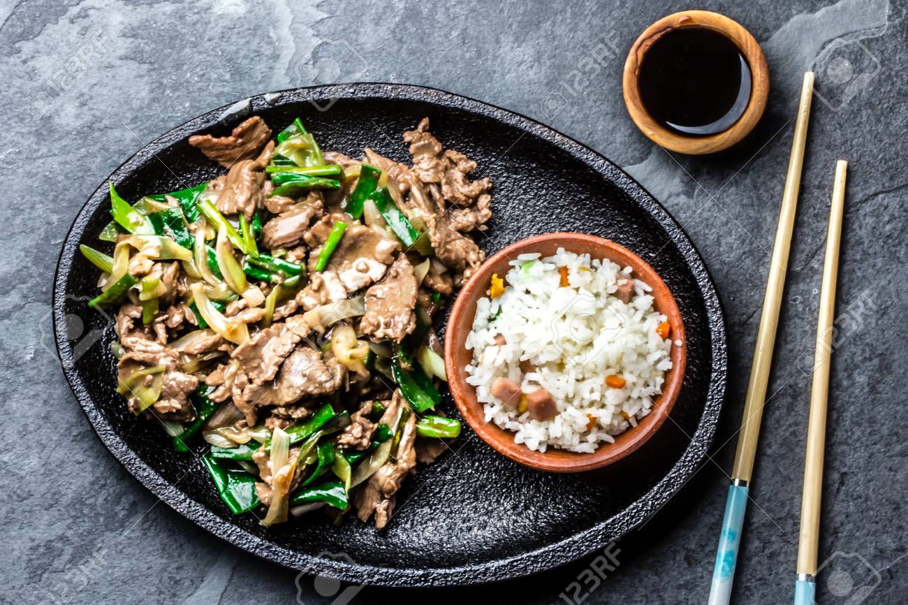 Traditional chinese mongolian beef stir fry on iron plate with rice and soya sauce on slate background. Top view, copy space - 71946091 Traditional chinese mongolian beef stir fry on iron plate with rice and soya sauce on slate background. Top view, copy space - 71946091