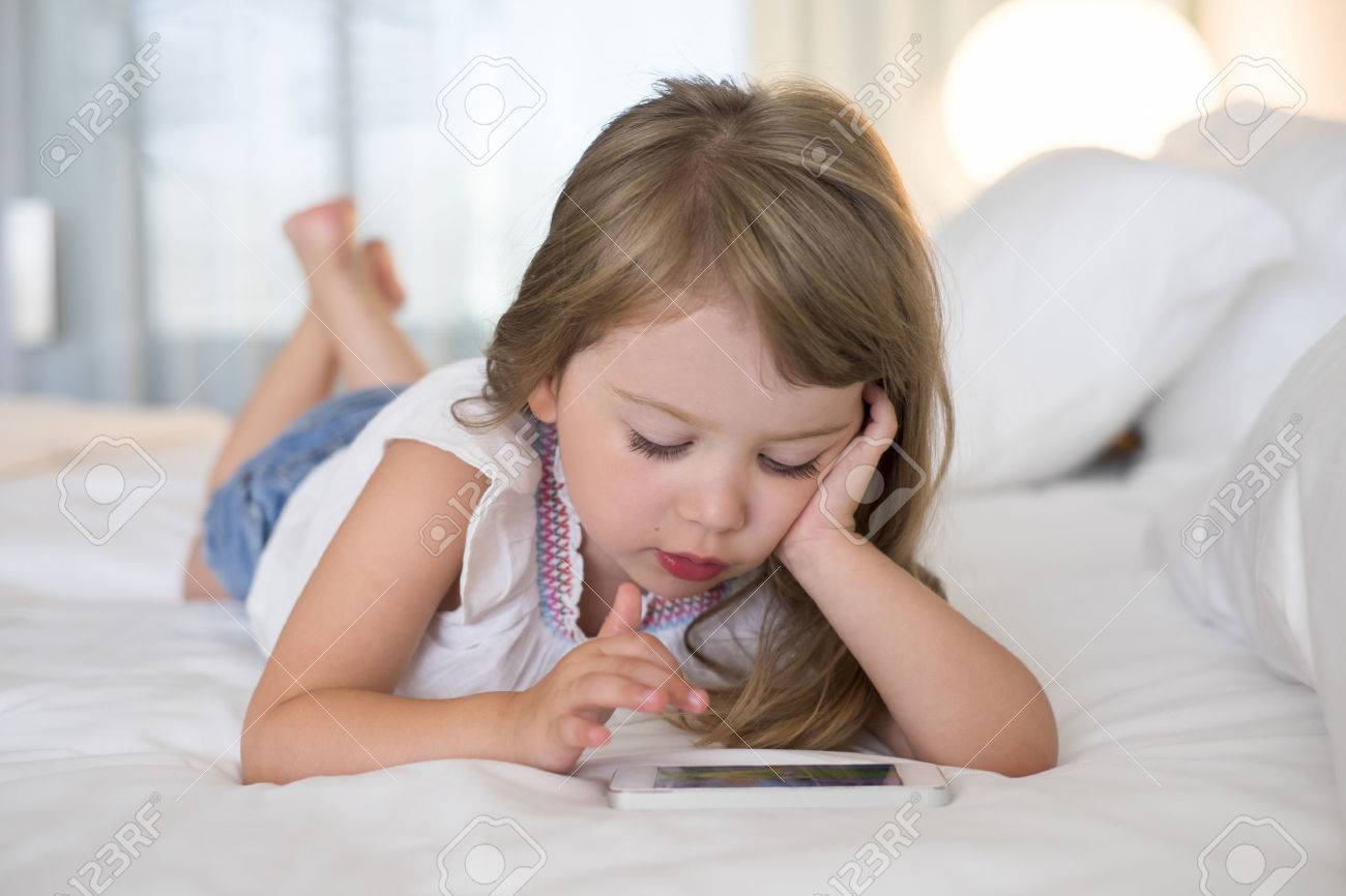 cute little girl using mobile phone at home stock photo picture and