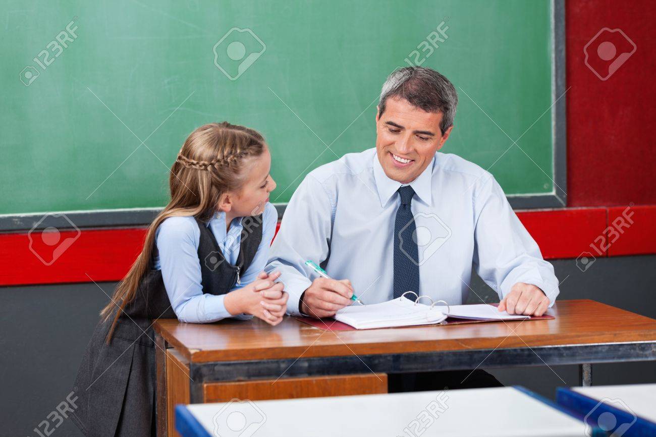 成熟した男性教師の教室で机に小さな女子高生にレッスンを説明します の写真素材 画像素材 Image