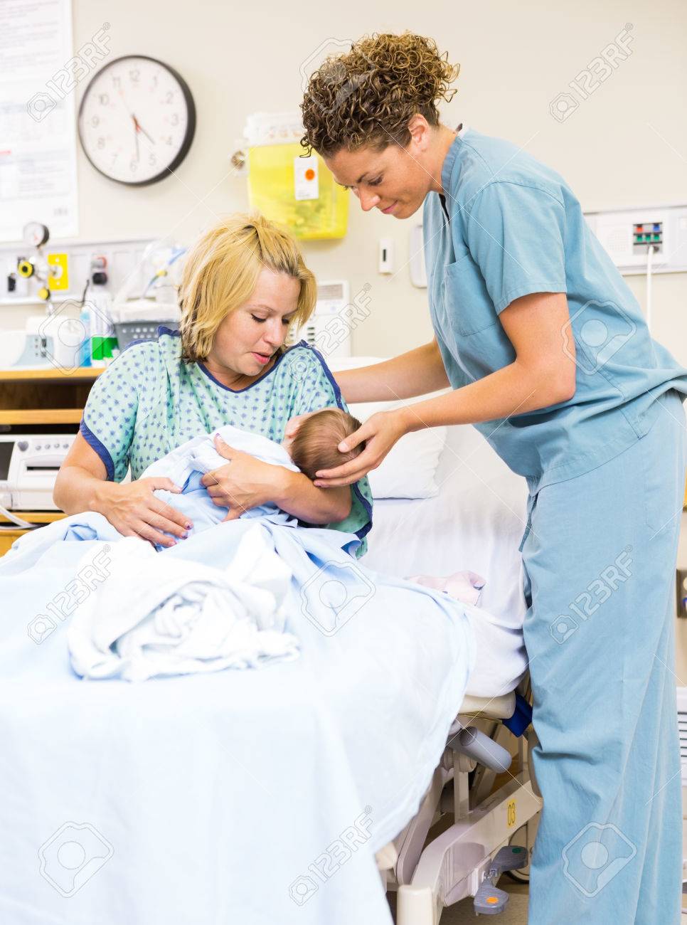 Mid adult nurse helping woman in holding newborn baby at hospital.. Mid adult nurse helping woman in holding newborn baby at hospital..