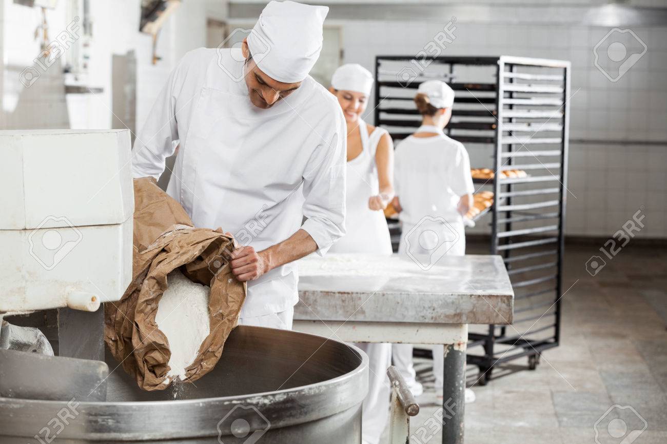 Mature male baker pouring flour in kneading machine at bakery - 53770593 Mature male baker pouring flour in kneading machine at bakery - 53770593