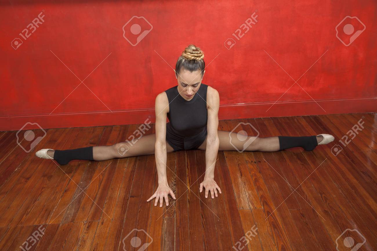 Full Length Of Young Ballerina Practicing Split On Hardwood Floor