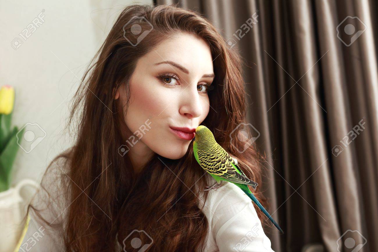 62987311-half-length-portrait-of-young-woman-with-cute-parrot-on-her-shoulder-giving-her-a-kiss-Stock-Photo.jpg