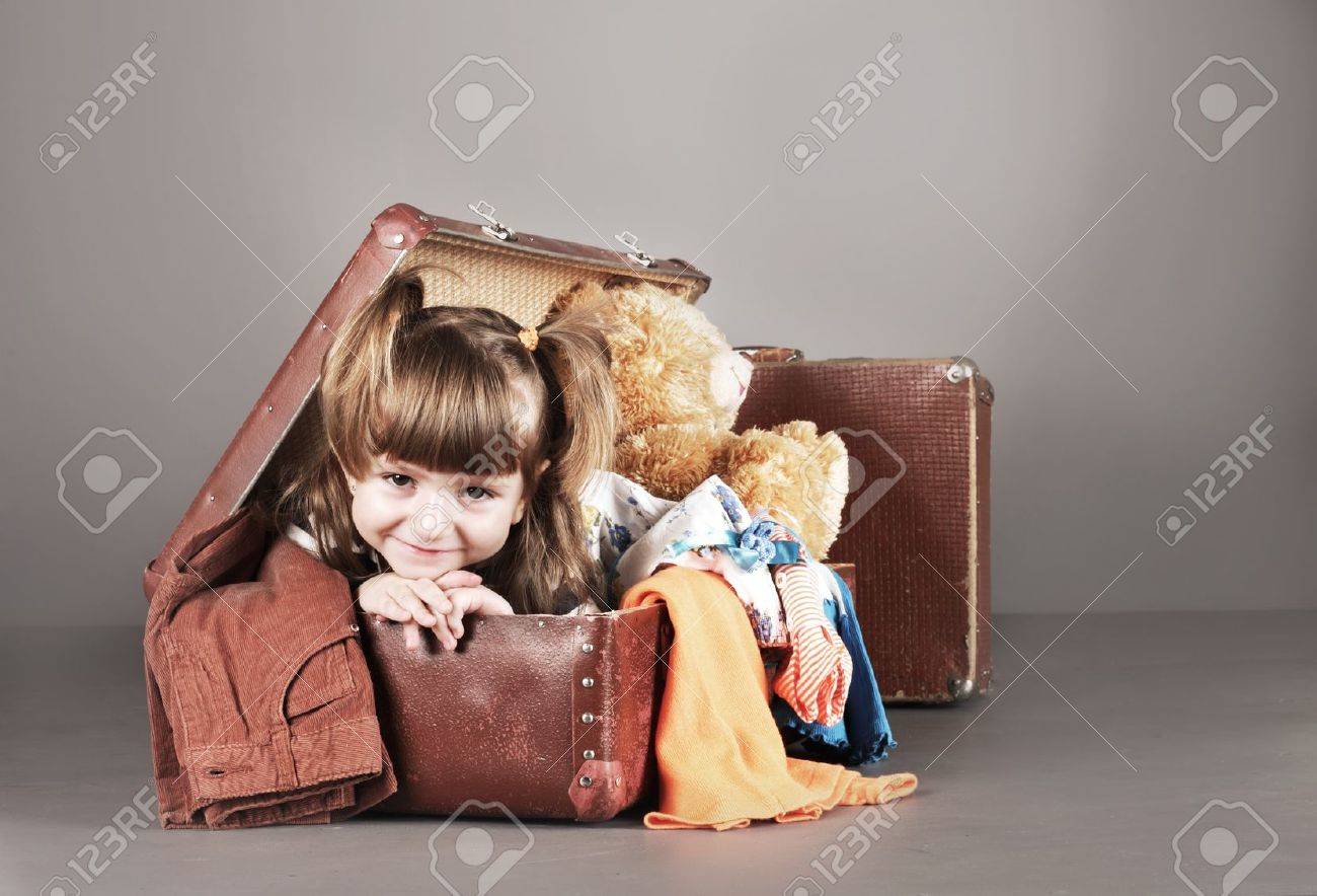 4 歳の女の子は喜んでおもちゃや服を着て古いスーツケースに座っています の写真素材 画像素材 Image 174