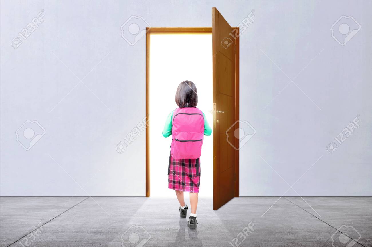 Rear View Of Asian Little Girl With A Backpack Walking Through