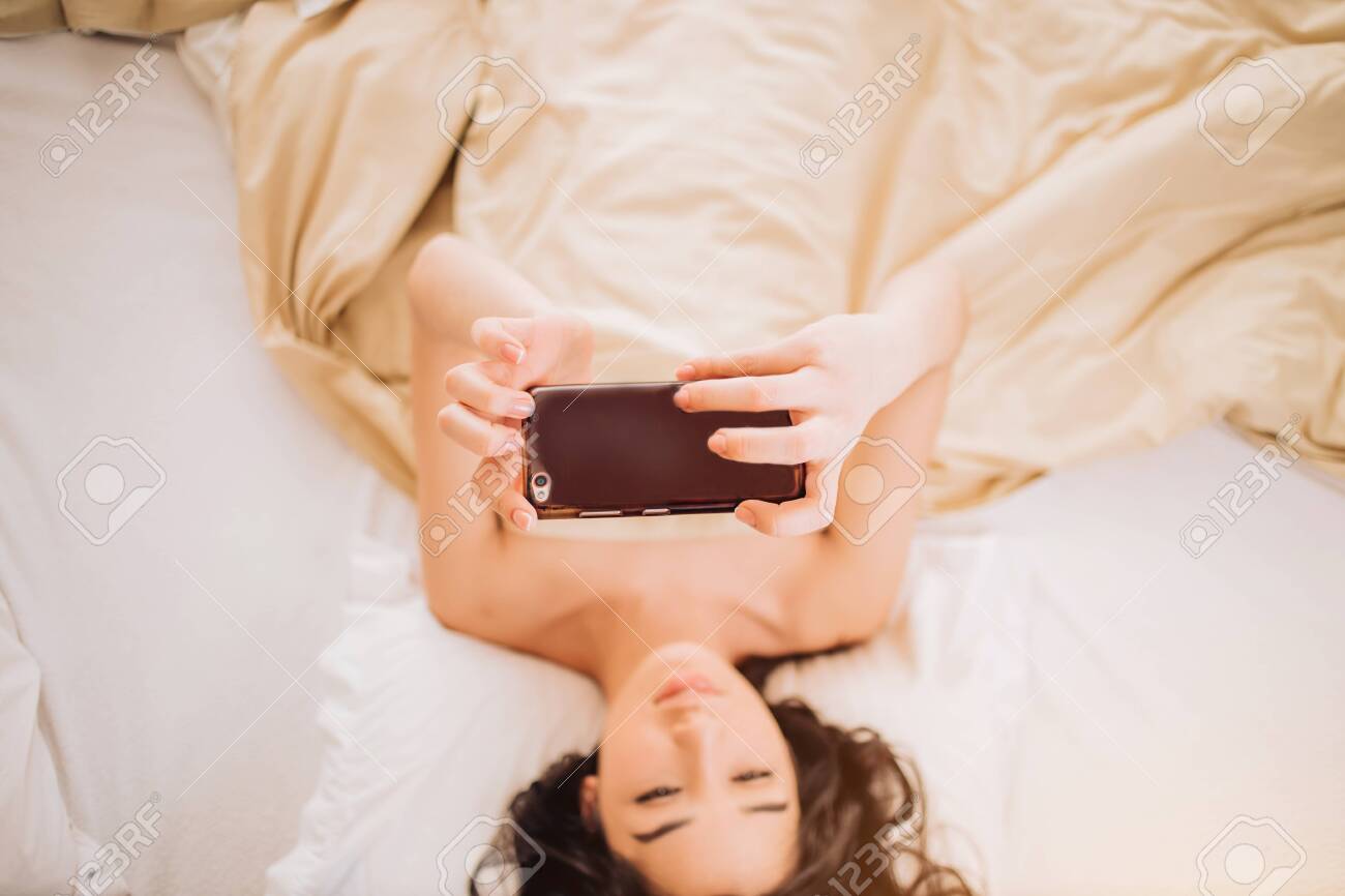 mobil naked girl selfie 官能的な若い女性が裸で毛布の下に横たわってスマートフォンを使って自分撮りをし、オンラインでビデオを見ている様子の上面図。焦点が合っている電話。人と現代のテクノロジー、リラクゼーションのコンセプト。の写真素材・画像素材  Image 123470686
