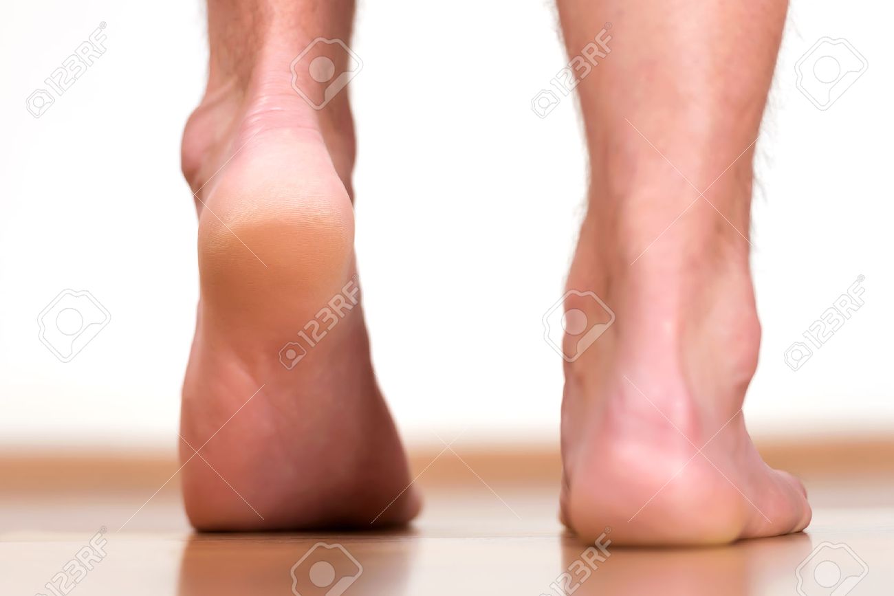 Pair of male feet stepping - view from back. - 46471106 Pair of male feet stepping - view from back. - 46471106