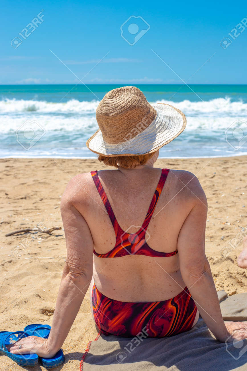海水浴　おばさん水着 水着姿の熟女が砂浜に座り、海を後ろ姿で眺める。ロシアの残りの年金受給者。の写真素材・画像素材 Image 181518309