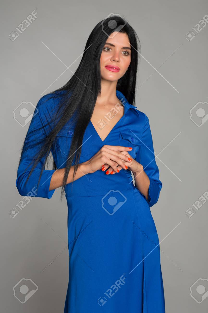 灰色の背景に青いドレスを着た黒髪の思いやりのある若い女性 26 歳の女性 の写真素材 画像素材 Image