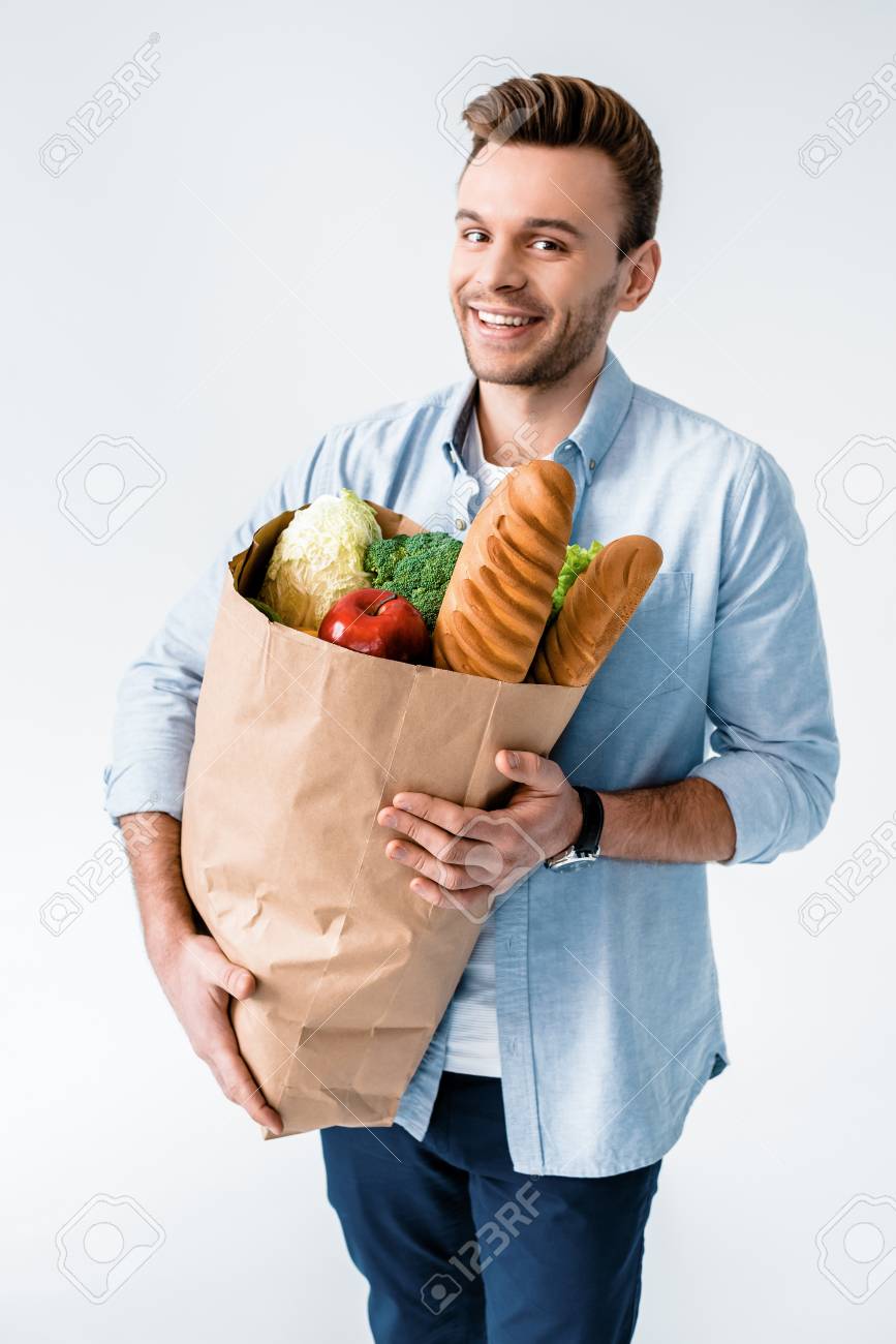 Hombre sosteniendo la bolsa de supermercado con productos y sonriendo a la cámara Hombre sosteniendo la bolsa de supermercado con productos y sonriendo a la cámara