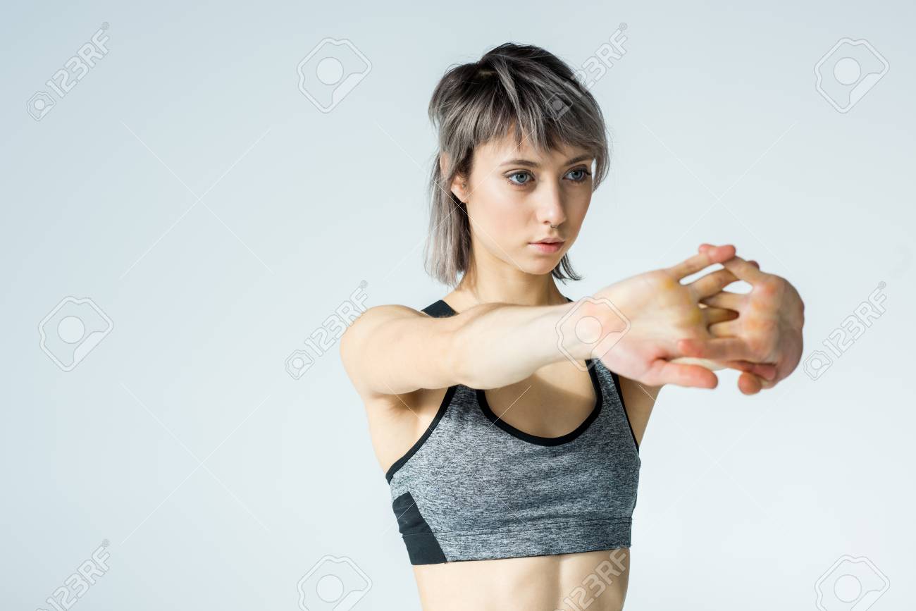 灰色の腕を伸ばすスポーツウェアの若い女性 の写真素材 画像素材 Image