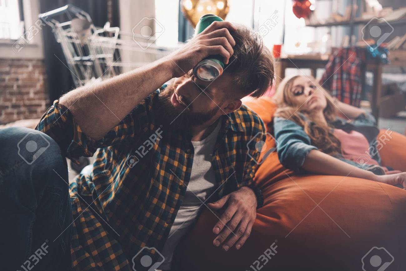 頭痛の持株を持つ男缶ビール 散らかった部屋で後ろの女 の写真素材 画像素材 Image 7704