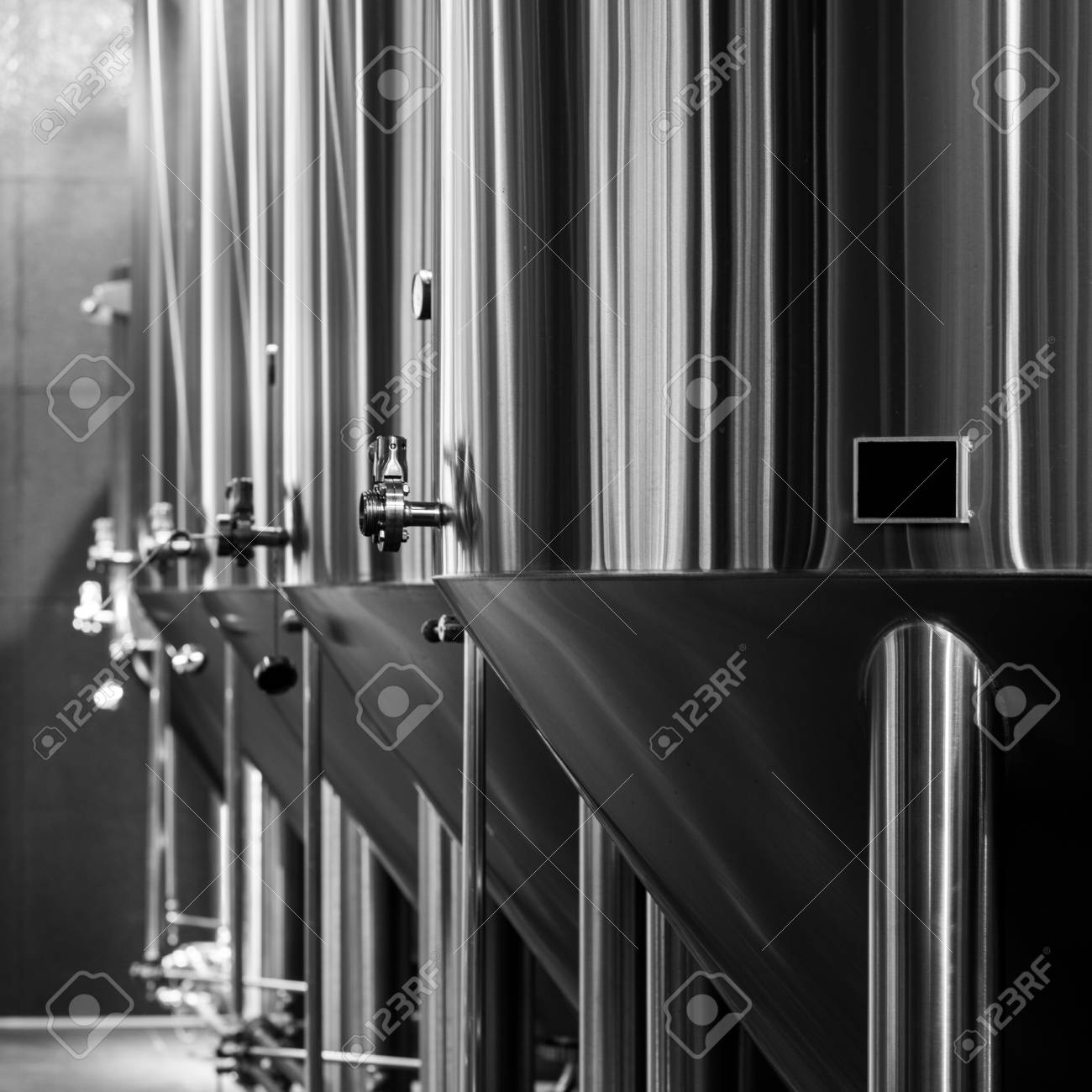 Black and white photo of modern brewery equipment with stainless tanks for the fermentation beer stock