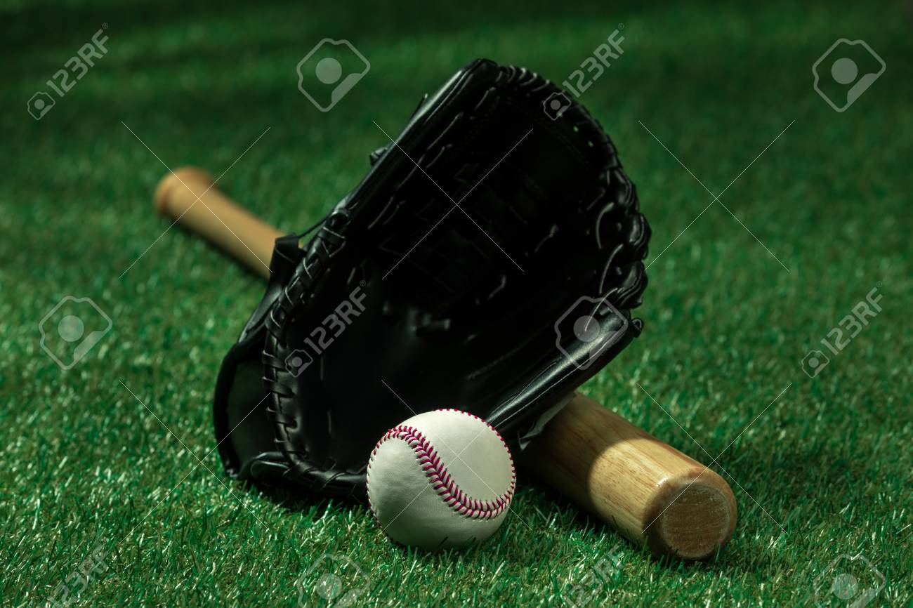 baseball bat glove and ball lying on green grass stock photo