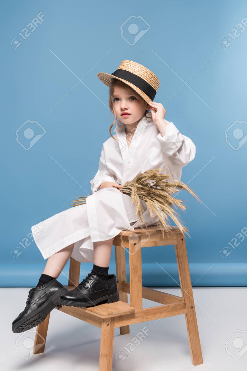 白いドレスと小麦の耳を持ってストロー カンカン帽を座っている美しい少女 の写真素材 画像素材 Image