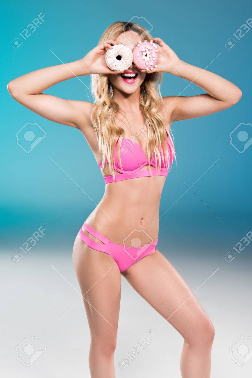 白人の女の子は水着で顔の前で甘いドーナツを保持 の写真素材 画像素材 Image