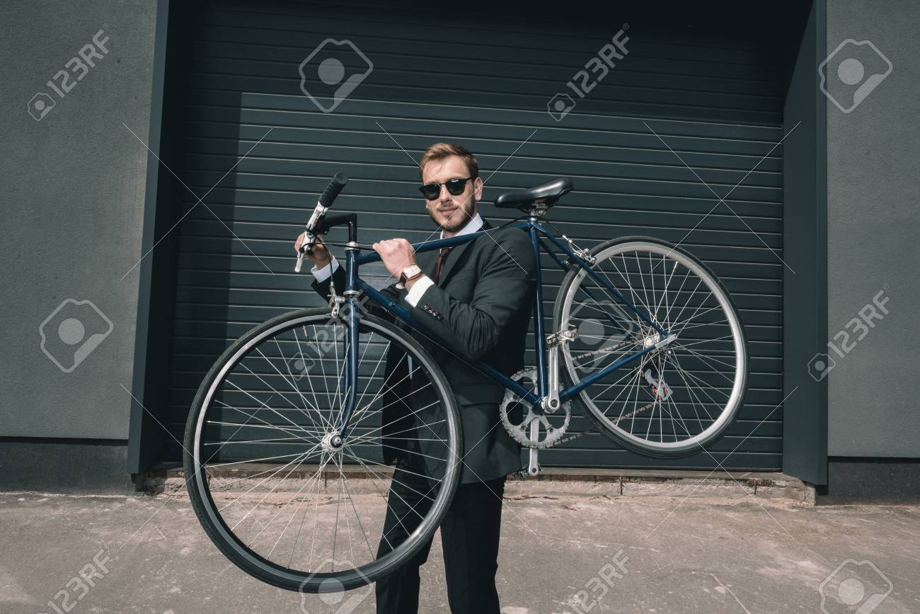 Elegante Hombre De Negocios Gafas De Sol Bicicleta Y Mirando A Cámara Fotos, Retratos, Imágenes Y Fotografía De Libres De Derecho. Image 83189279.