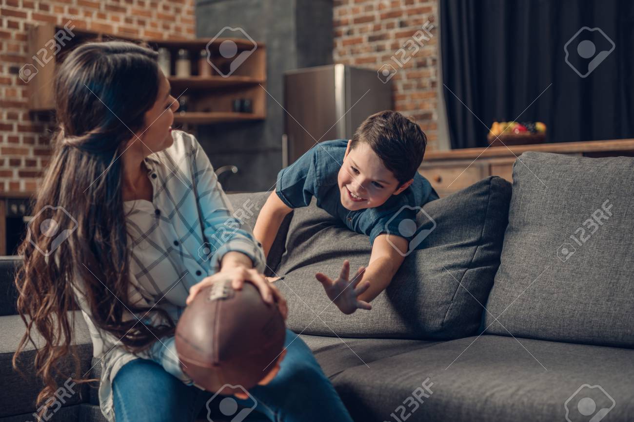 little boy and his young mother playing with a rugby ball on stock