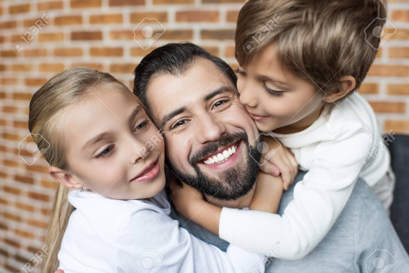portrait of little siblings hugging happy father stock photo
