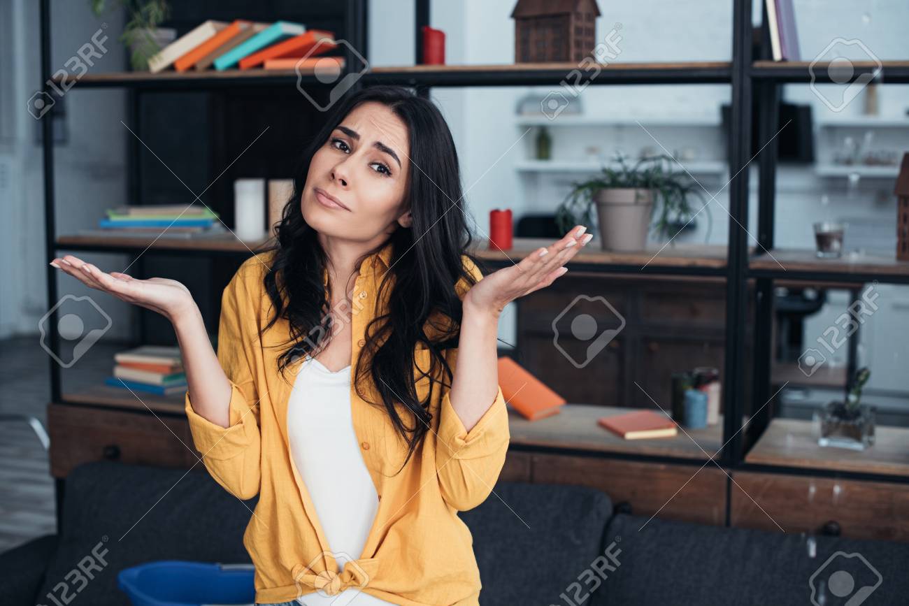 Confused Woman Standing With Hands Up Under Leaking Ceiling In